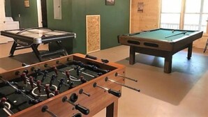A pool table, a foosball table, and a billiards table in a room with green walls and wooden paneling. - Mi Casa es su Casa (Blue Ridge)