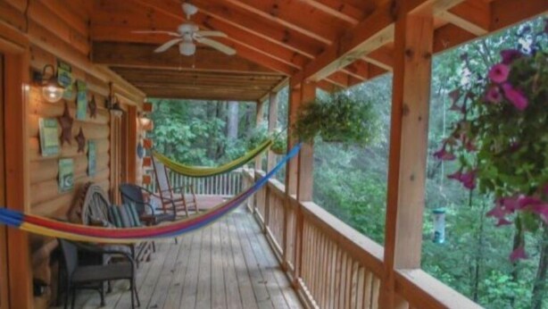 A wooden deck with a hammock, chairs, and a view of the forest. - Mi Casa es su Casa (Blue Ridge)