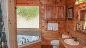 Une salle de bain rustique, avec une cabine en bois, une baignoire, des toilettes et un lavabo.
