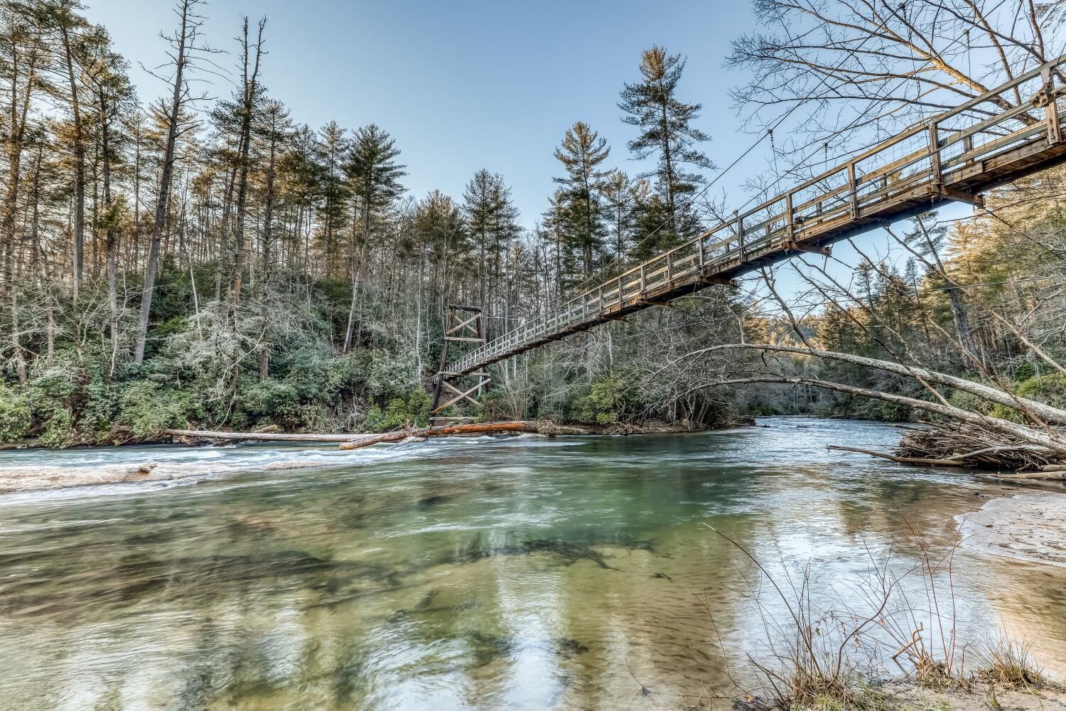 Een houten brug over een rivier, omringd door bomen.