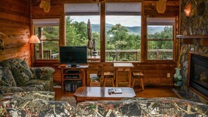 A cozy cabin interior with a television, seating area, and a fireplace. - Okeana (Blue Ridge)