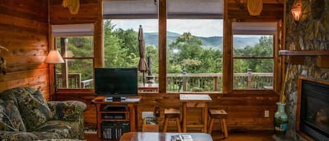 A cozy cabin interior with a television, seating area, and a fireplace.