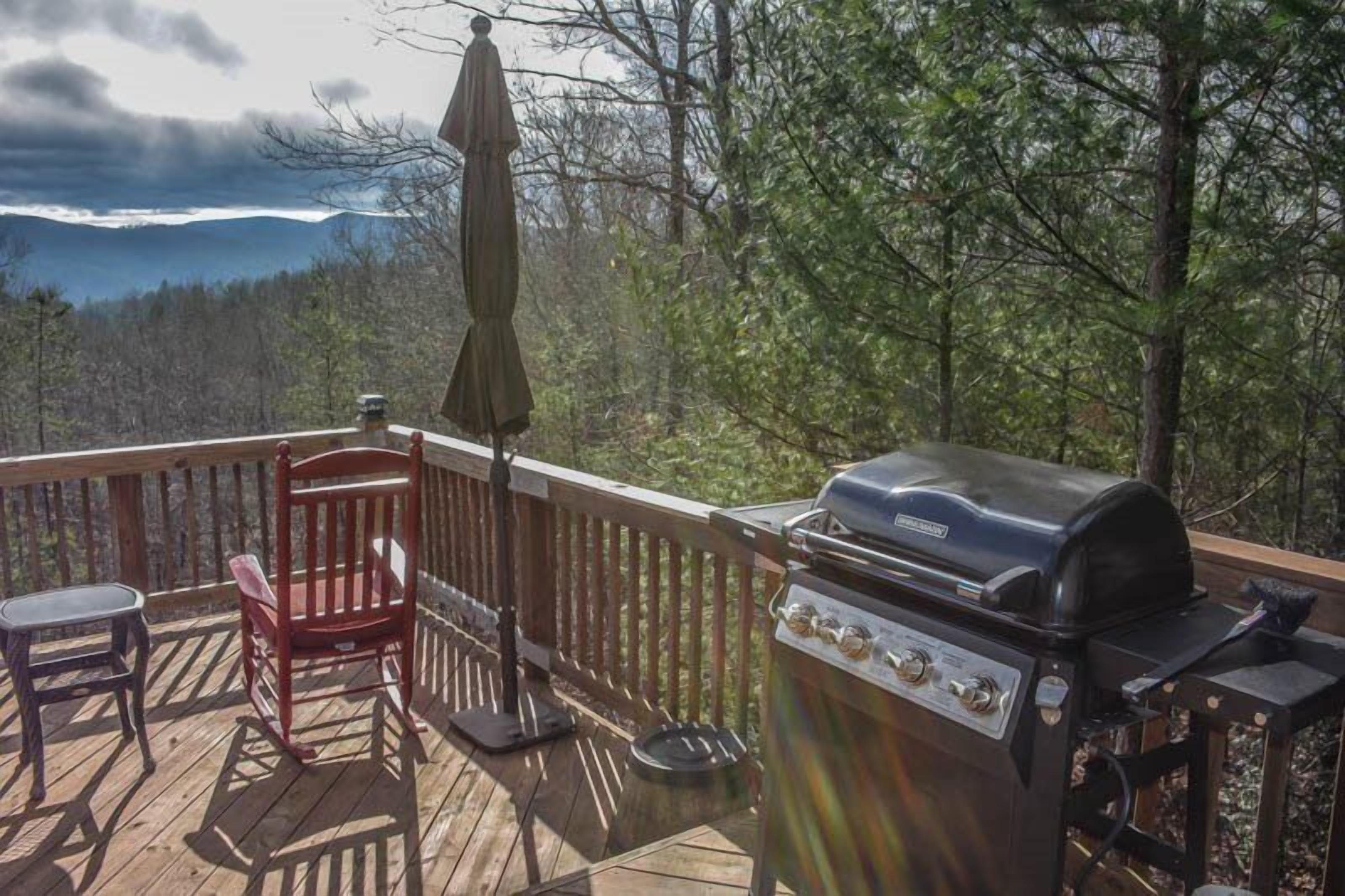 Une terrasse avec un barbecue, une chaise berçante et une petite table.
