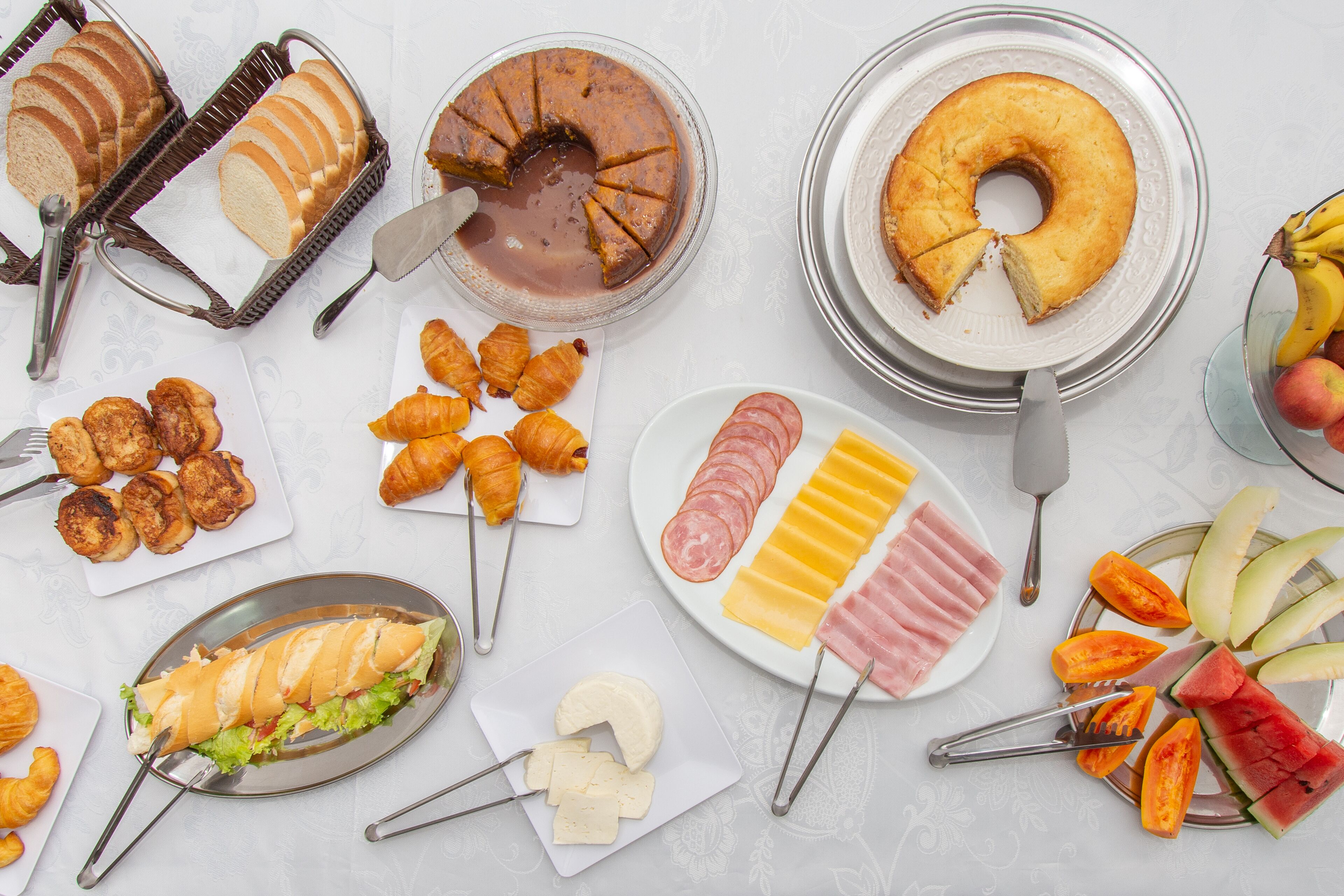 A table with various food items including bread, pastries, cheese, and fruits.