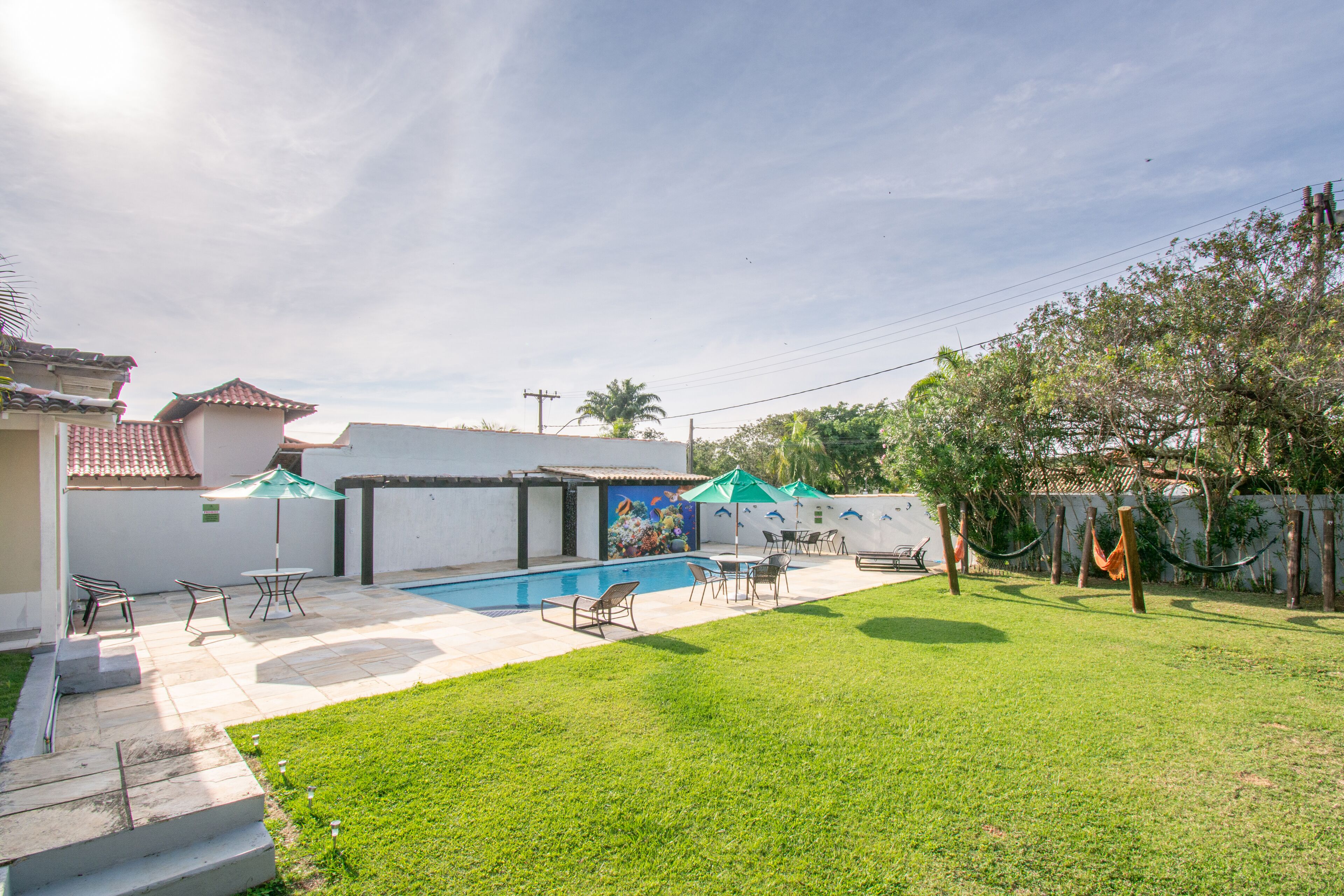 A backyard with a swimming pool, patio furniture, and a mural on the wall.