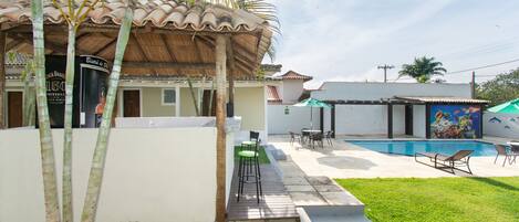 A house with a swimming pool, outdoor seating, and a mural on the side.