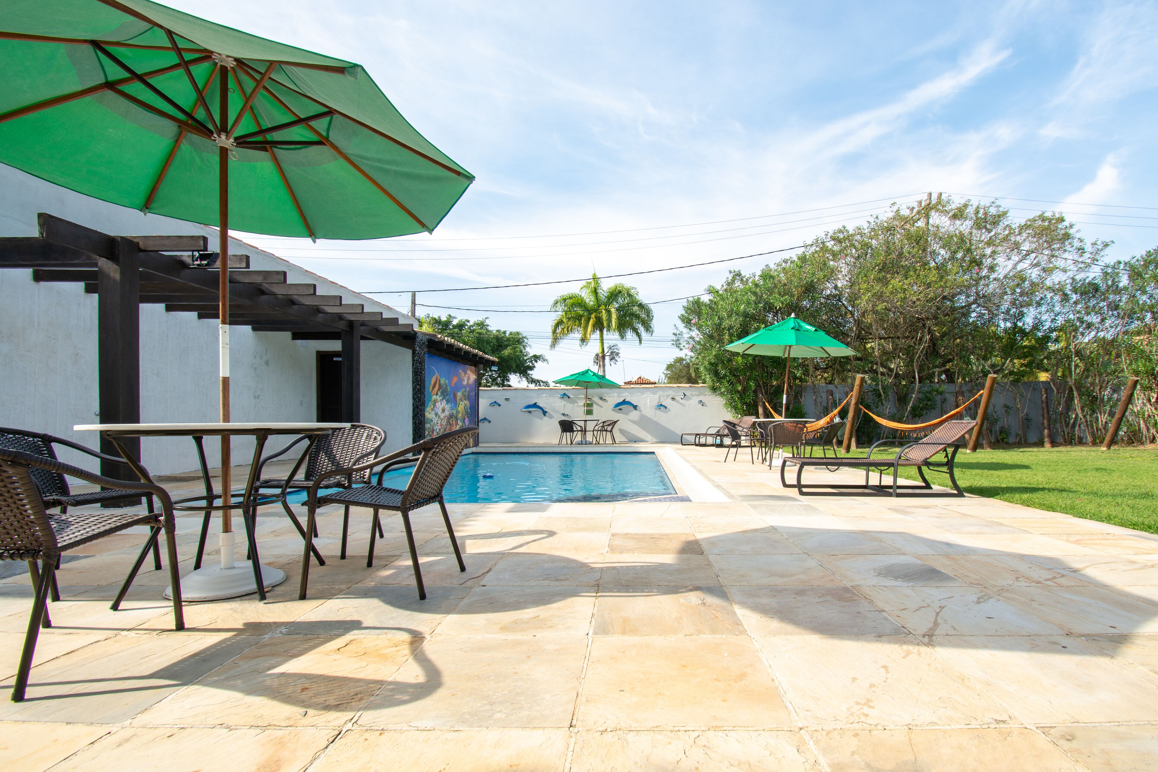 A backyard with a swimming pool, outdoor seating, and a hammock.