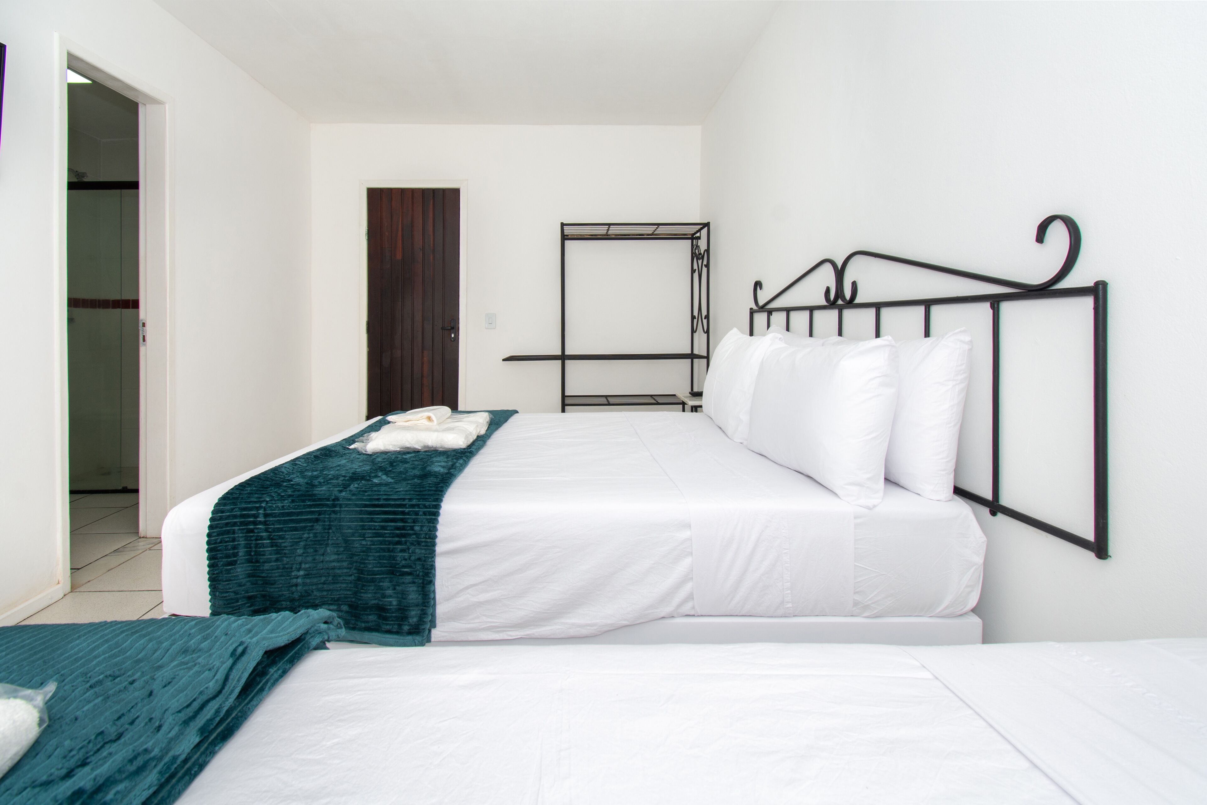 Une chambre avec un lit simple, une porte en bois et un cadre de lit en métal.