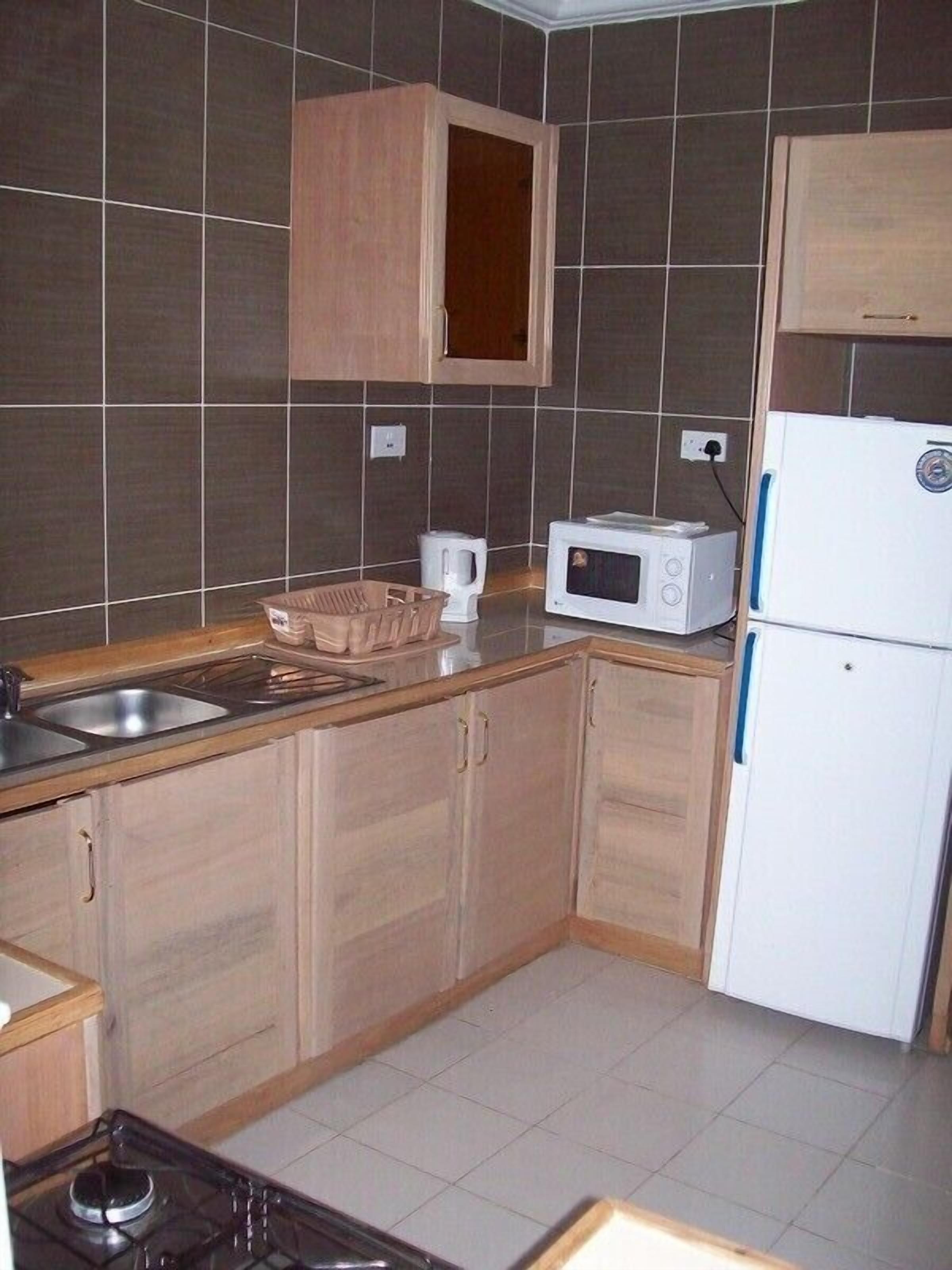 Una cocina con armarios de madera, microondas, hervidor y estufa.
