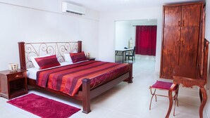 Een slaapkamer met een bed, nachtkastje en een houten garderobe.