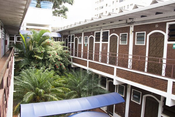 A multi-story building with a brick facade, multiple windows, and a balcony with a metal railing. - Hotel JS (Alfenas)