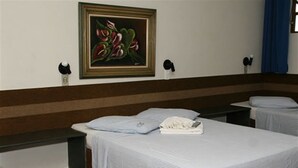 A hotel room with a large bed, a bedside table, a nightstand, a framed painting on the wall, and a window with curtains. - Hotel JS (Alfenas)