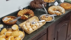 A buffet with various baked goods and pastries, including bread, rolls, and cakes. - Hotel JS (Alfenas)