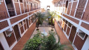 A courtyard with brick buildings, a central pathway, and greenery. - Hotel JS (Alfenas)