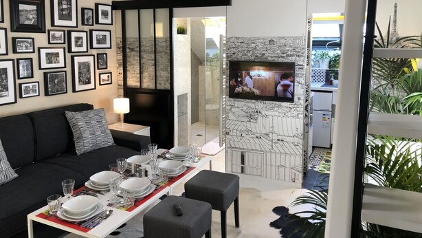 A modern living room with a dining area, featuring a fireplace, a television, and a wall adorned with framed photographs. - A5G Skyglass (París)
