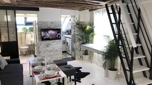 A modern living room with a dining area, a kitchen, and a TV mounted on the wall. - A5G Skyglass (París)