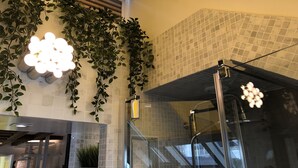 A bathroom with a glass shower enclosure, tiled walls, and a ceiling with a yellow accent. - A5G Skyglass (París)
