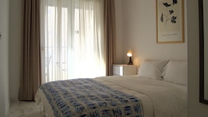 A bedroom with a bed, a nightstand, a lamp, and a framed picture on the wall. - Yeshill Apartments (Budva)