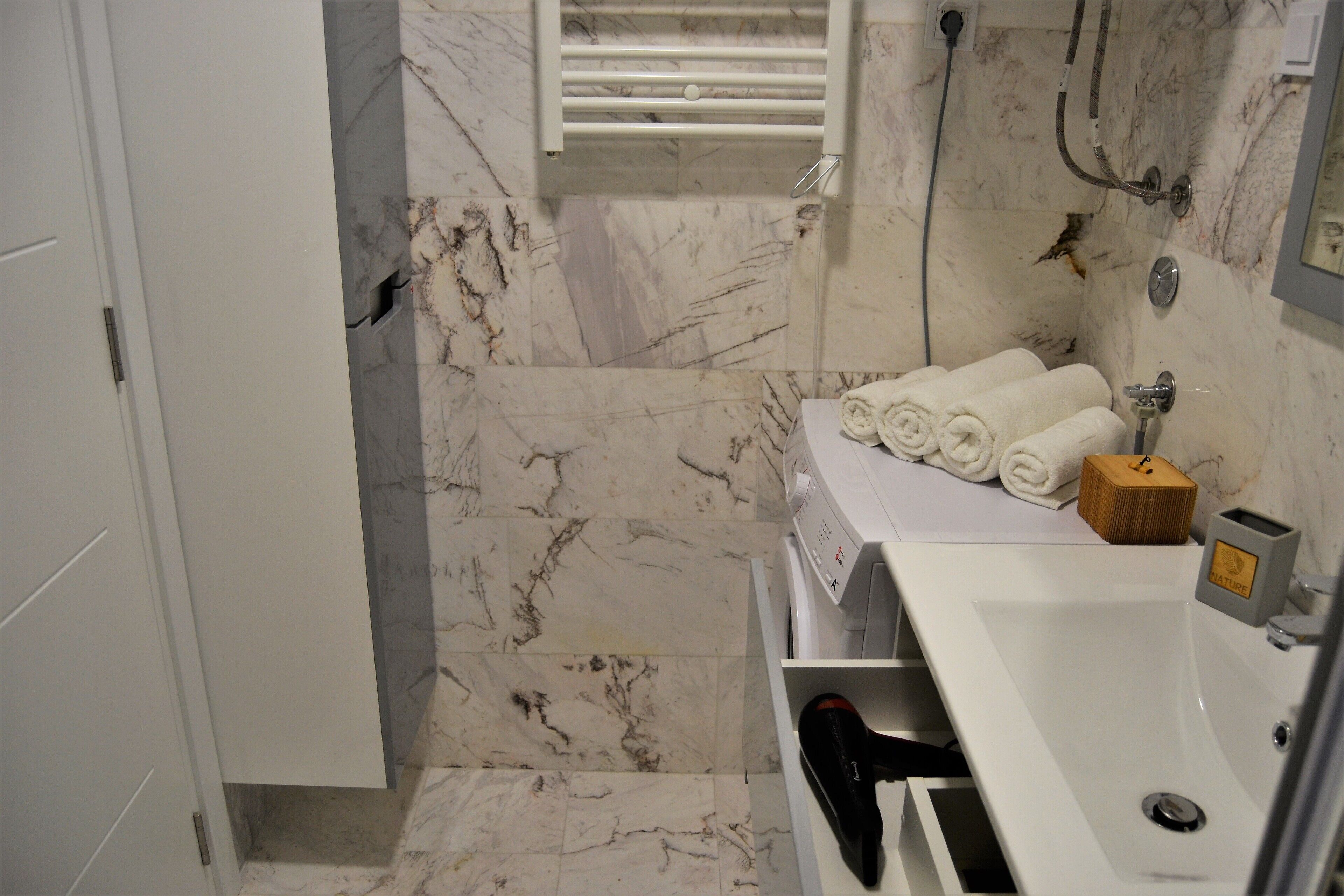Une salle de bain avec un sol en marbre, un lavabo blanc et un porte-serviettes.