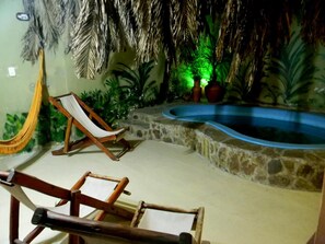 Un espace piscine agrémenté d’un mur en pierre, d’un hamac et de deux chaises longues en bois.