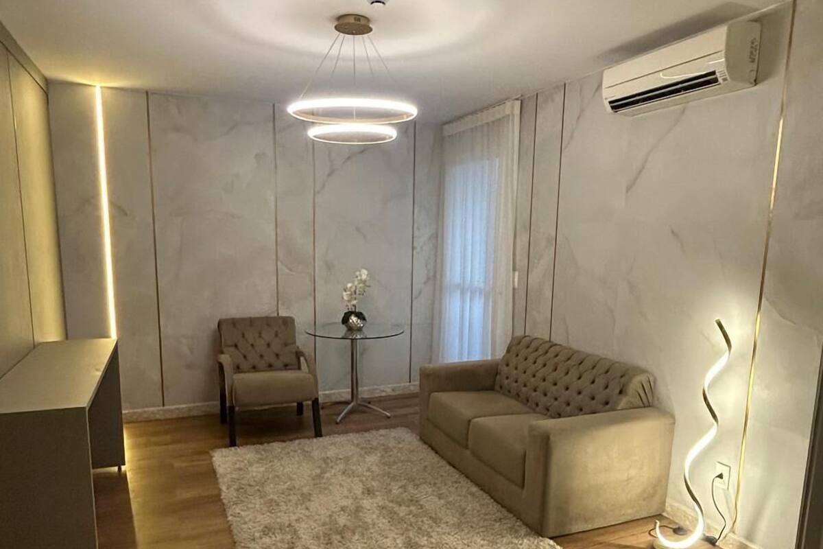 A modern living room with a sofa, armchair, and a small side table.