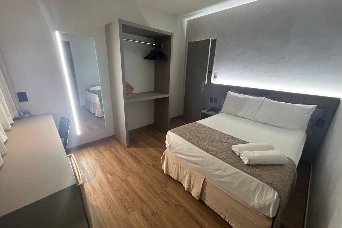A bedroom with a bed, a wardrobe, a mirror, and a desk.