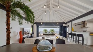 A modern interior with a dining area, a large plant, and a view of the outdoors.