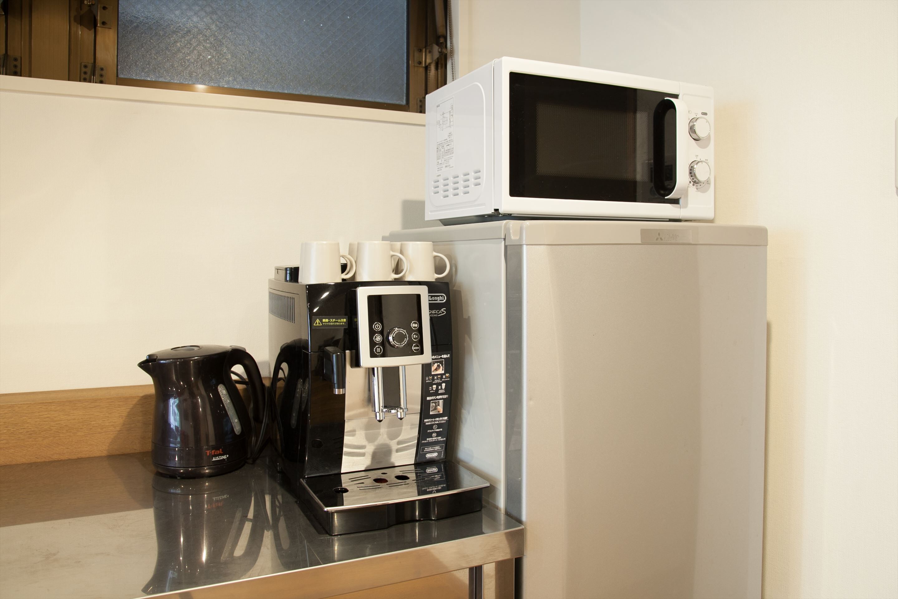 A kitchen with a coffee maker, a microwave, and a kettle on a countertop.