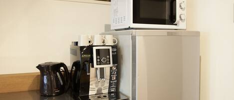A kitchen with a coffee maker, a microwave, and a kettle on a countertop.