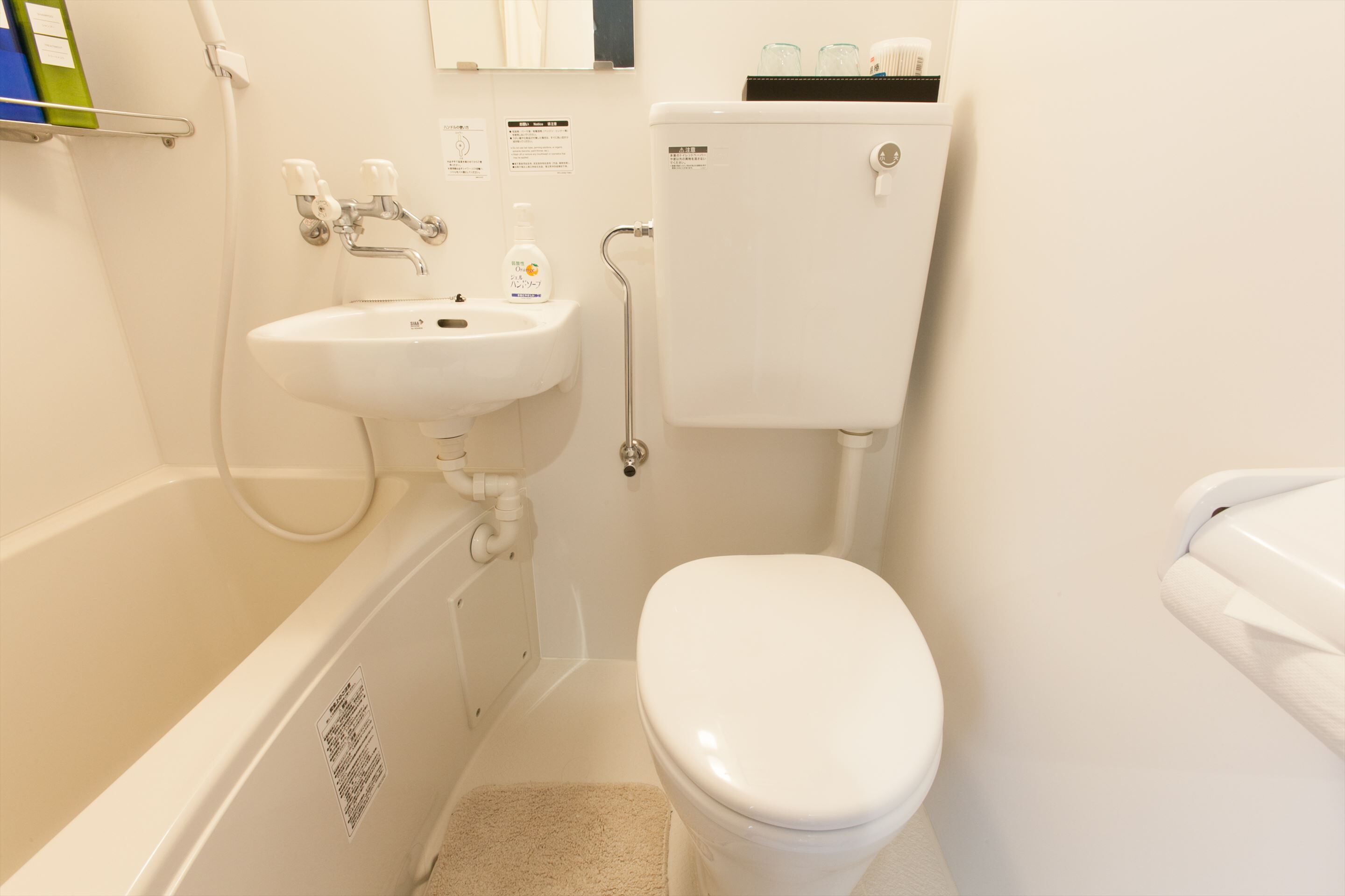 Un baño pequeño y limpio con lavamanos, inodoro y bañera blancos.
