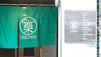 A green curtain with the Cocoro logo and a welcome sign in multiple languages.