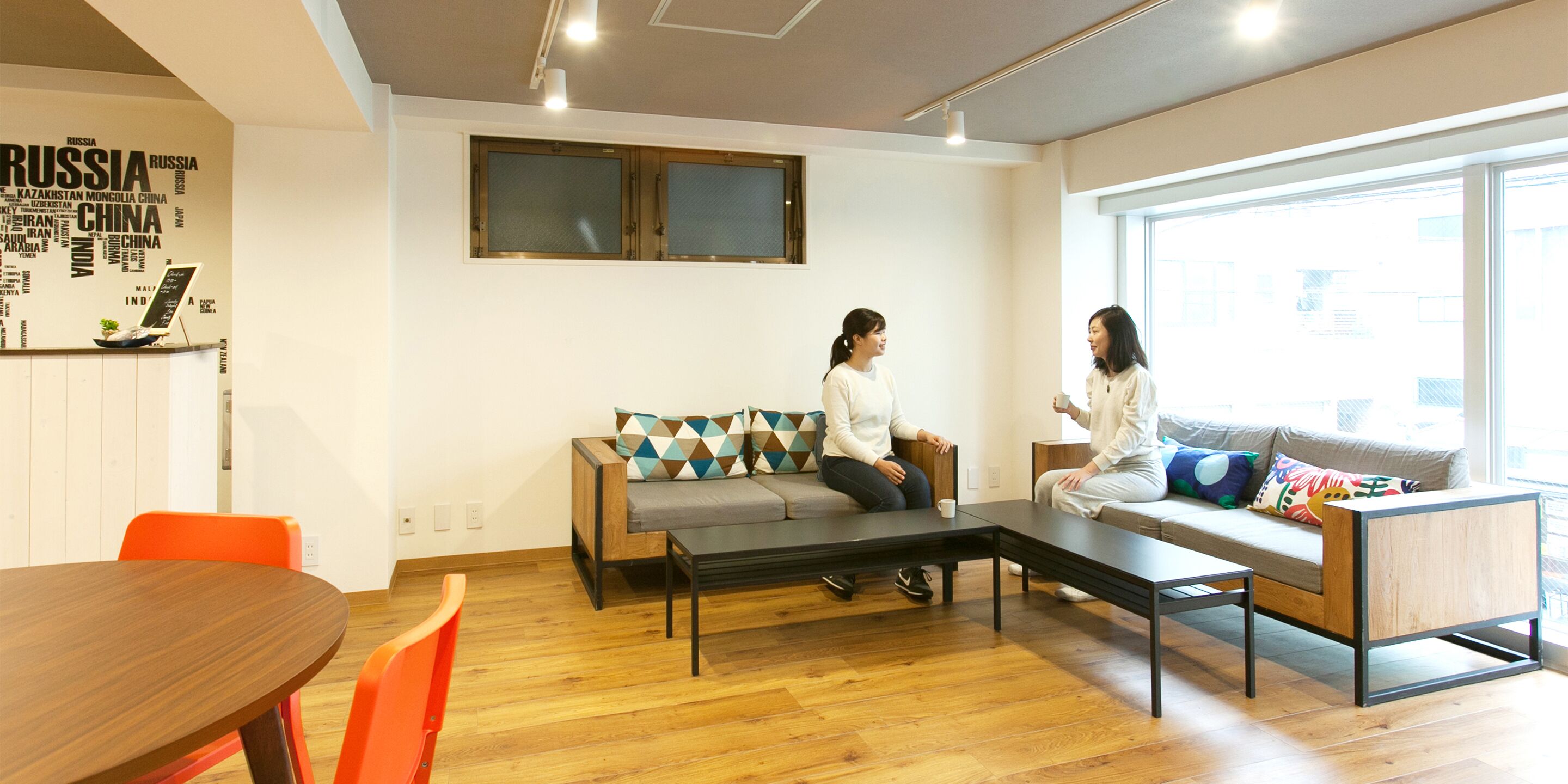 Un salon moderne avec un canapé, une table basse et une table à manger. Deux personnes sont assises sur le canapé.