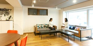Un salon moderne avec un canapé, une table basse et une table à manger. Deux personnes sont assises sur le canapé.