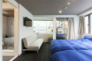 Une chambre d’hôtel comprenant un lit, un canapé, une télévision et une salle de bain avec douche.