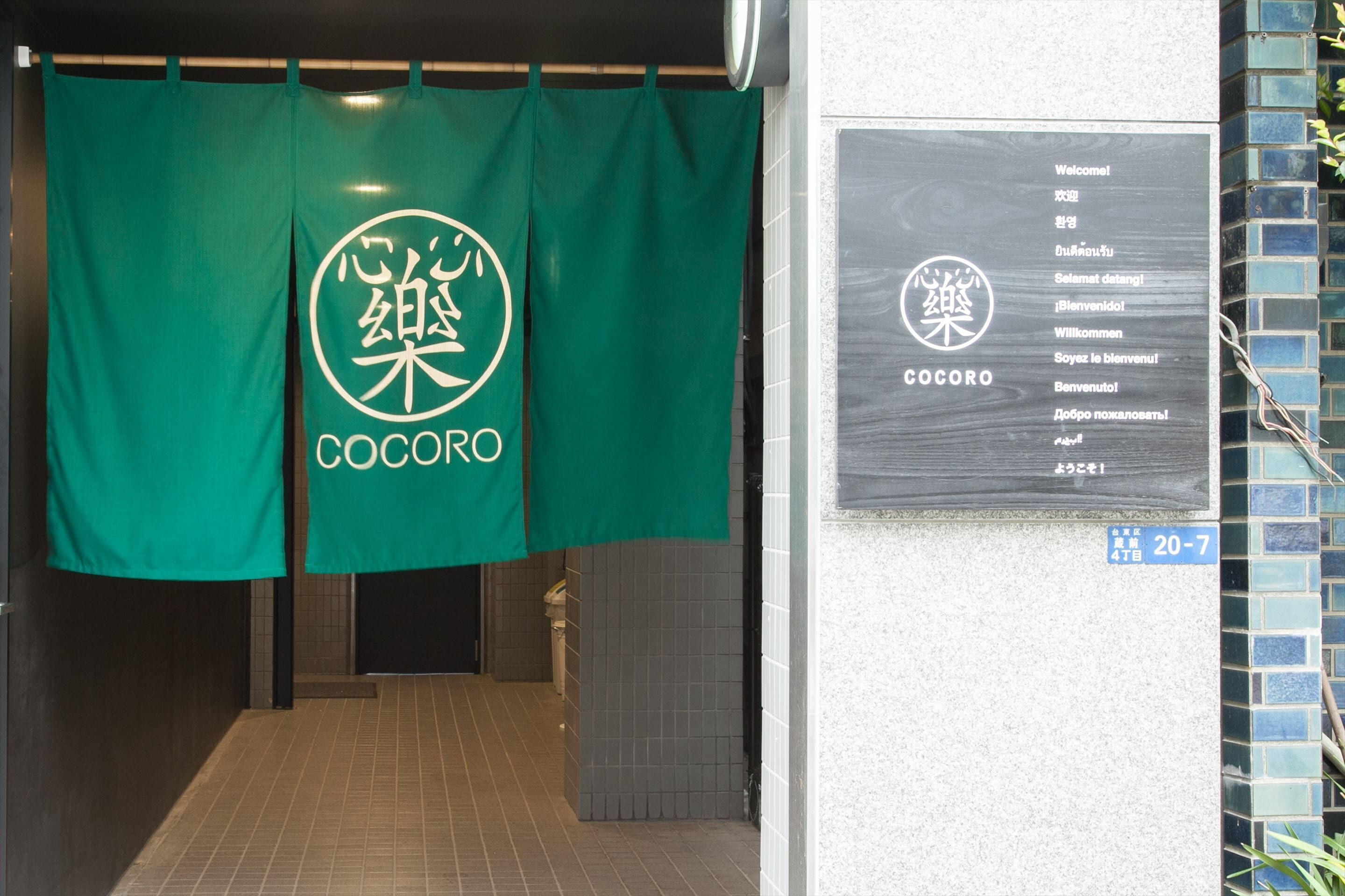 A hallway with a green banner displaying the Cocoro logo and a welcome sign with multilingual greetings.