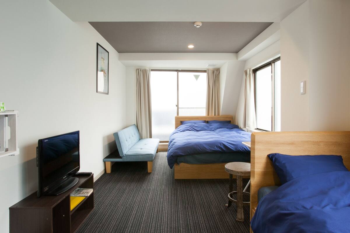 A hotel room with a bed, a TV, a small table, and a window.
