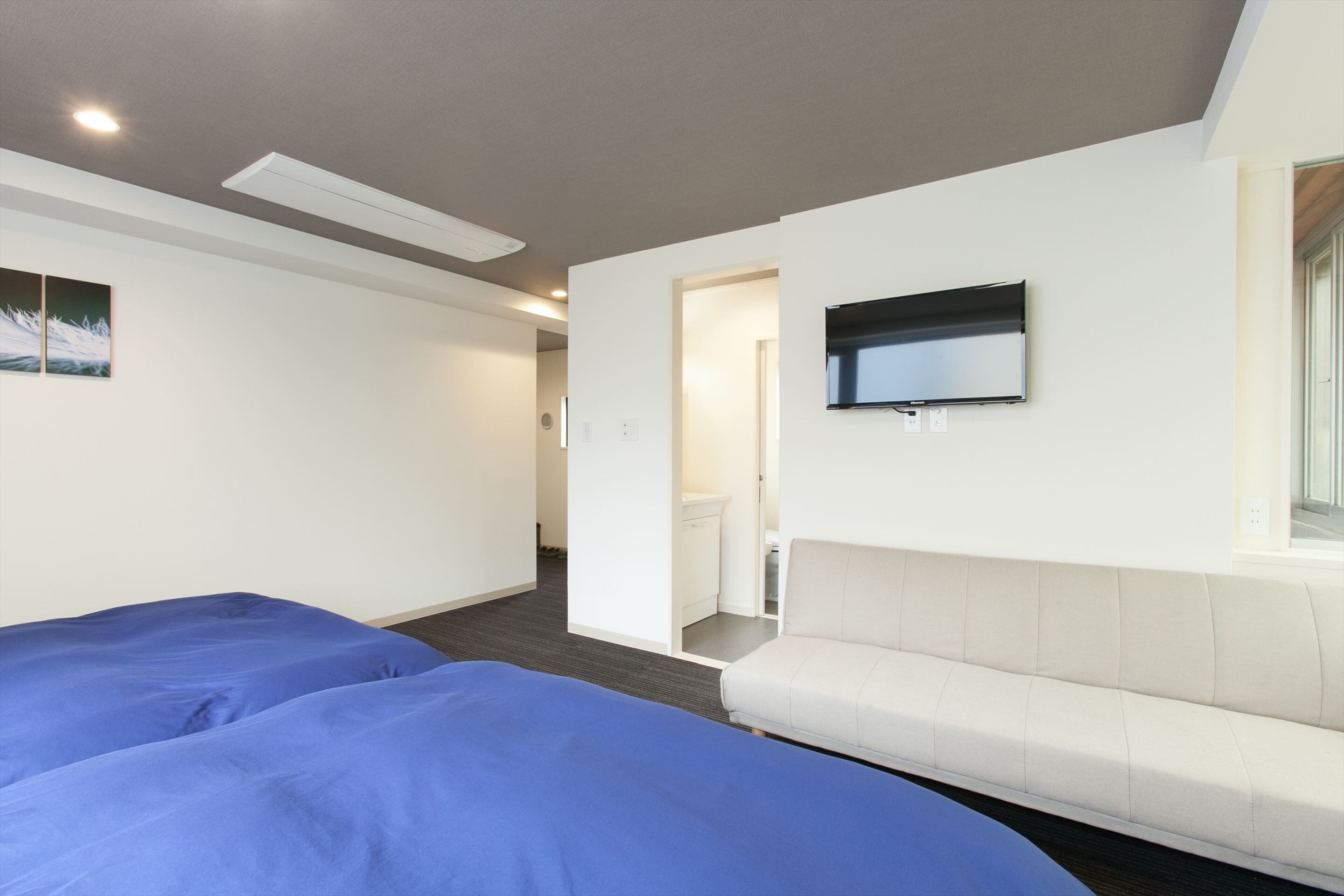 A hotel room with two beds, a TV, and a sofa.