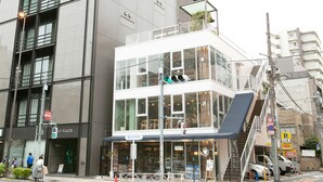 A multi-story building with a ground-level cafe, large windows, and a visible staircase leading to an upper floor.