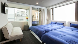 A hotel room with a bed, a sofa, a TV, and a window with curtains.