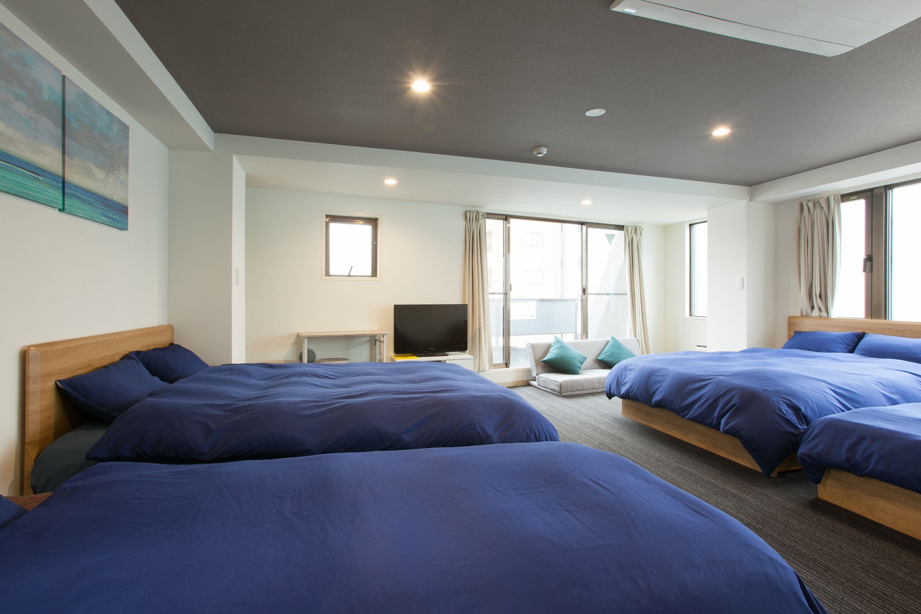 Habitación de hotel con dos camas, televisión y ventana con cortinas.