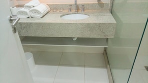 A bathroom with a granite countertop, a white sink, and a glass shower enclosure.