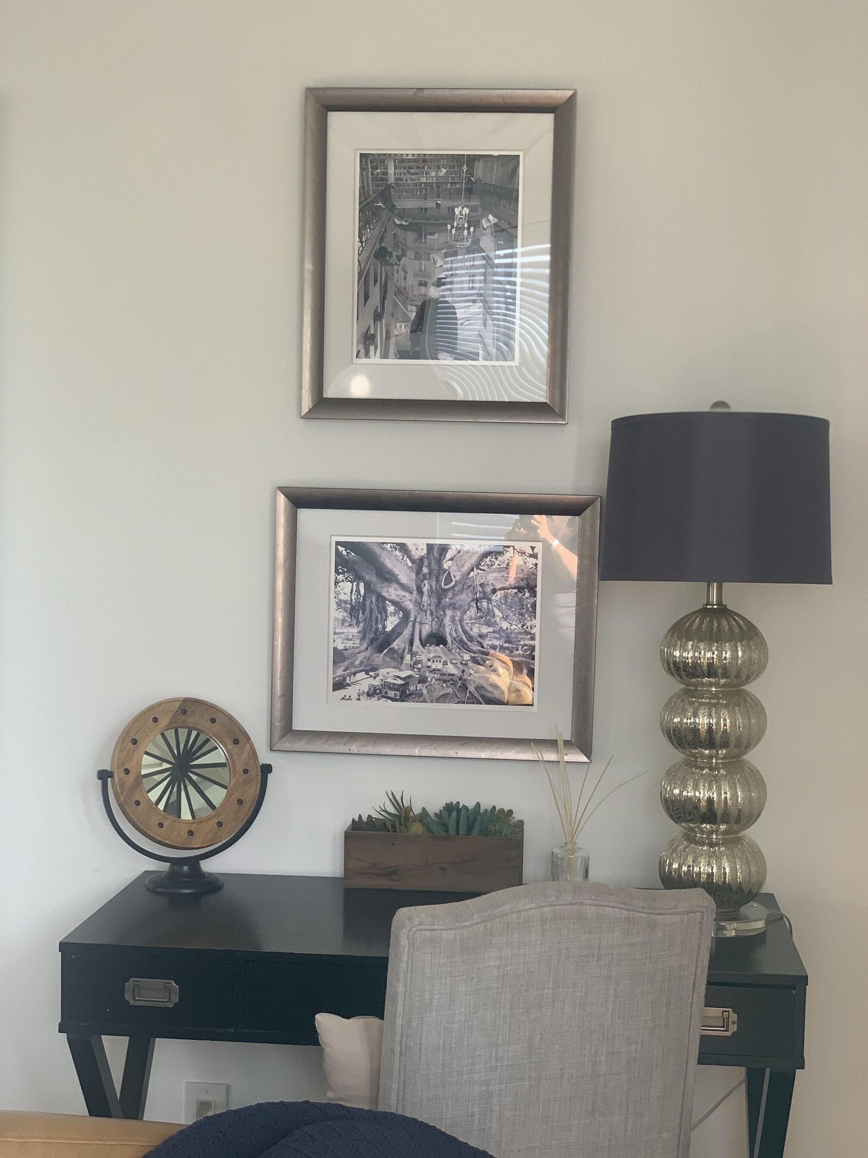 A desk with two framed pictures, a lamp, and a decorative object.