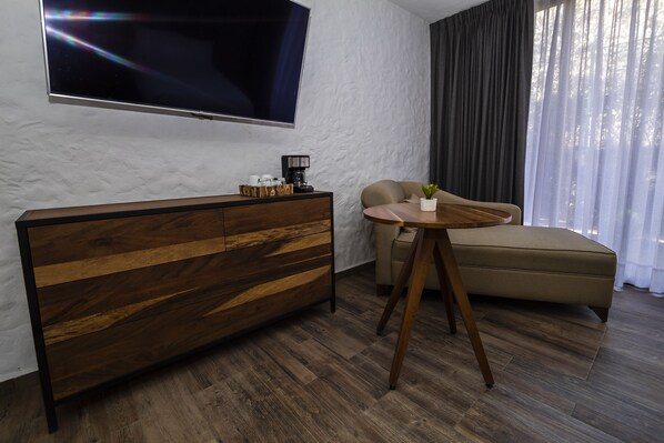 Una sala de estar moderna con una consola de madera, una mesa de centro redonda, un sofá color beige y un televisor grande montado en una pared con textura.