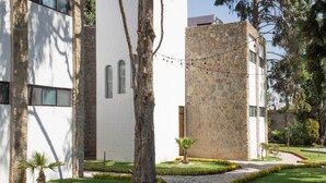 Um pátio com edifícios de pedra, um caminho pavimentado e uma palmeira.
