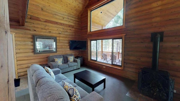 A log cabin interior with a sofa, a coffee table, a TV, and a fireplace. - Pine Mt Lodge* 6Br, 3.5Ba, Wifi, 42 Miles to YNP (Island Park)