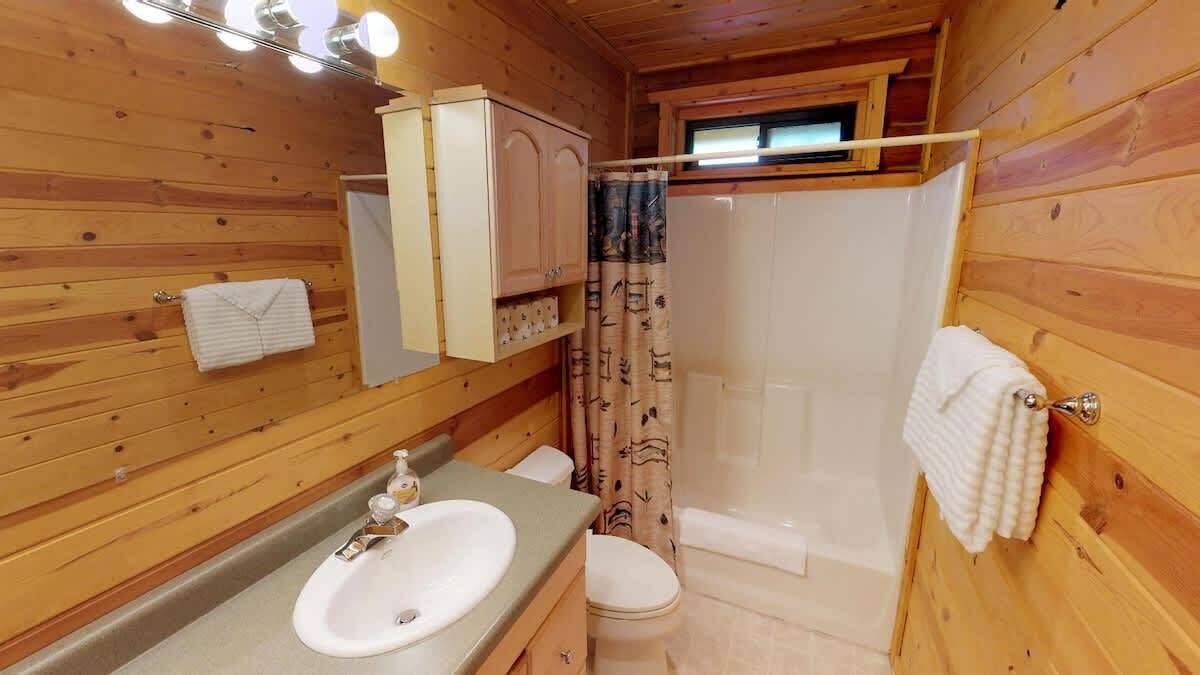 Ein Badezimmer einer Holzhütte mit Waschbecken, Toilette und Dusche.