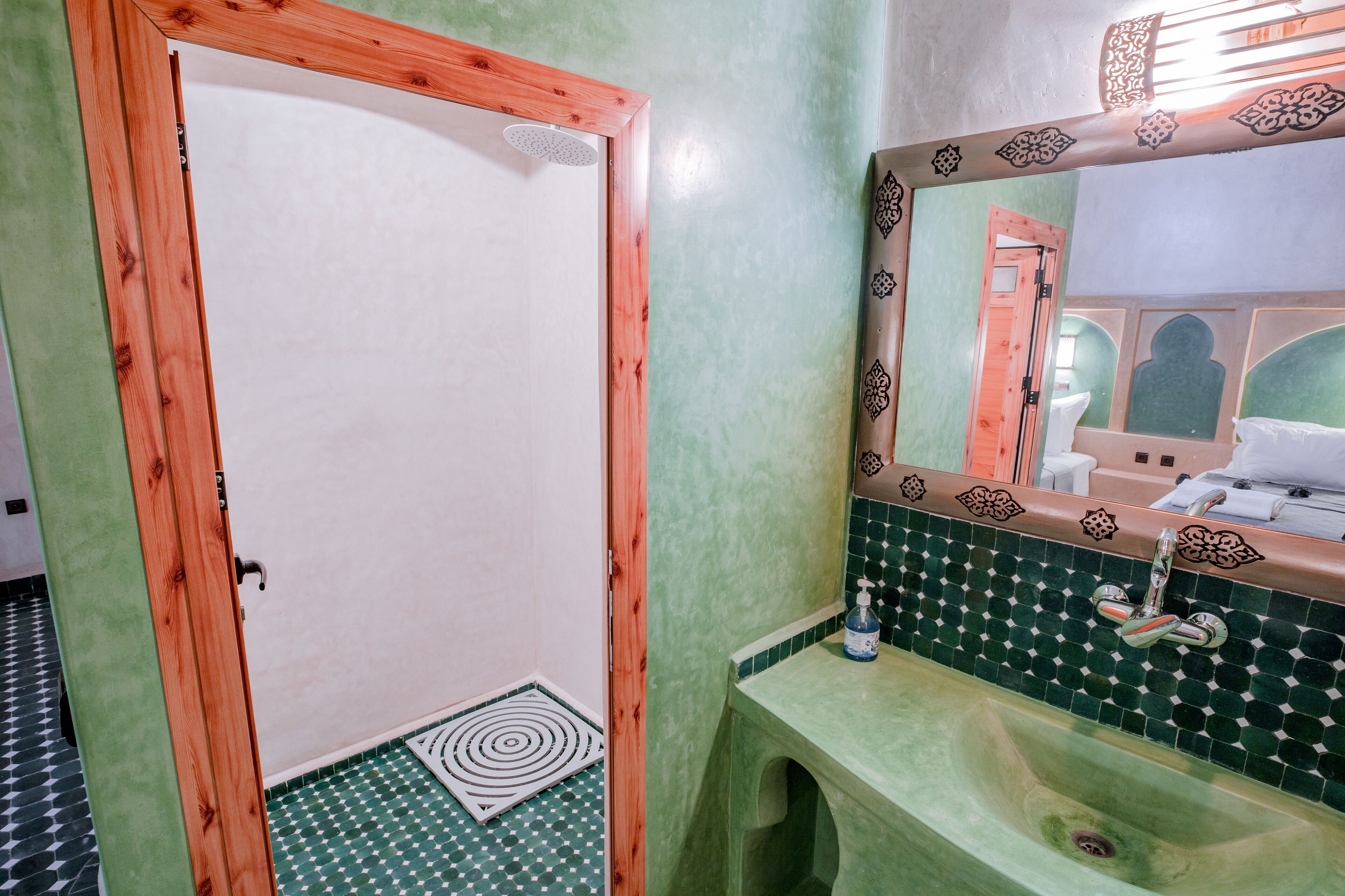 A bathroom with a wooden door, a green sink, and a tiled backsplash.