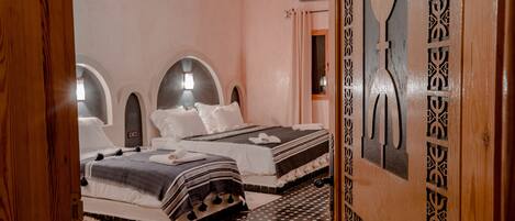 A hotel room with two beds, a patterned floor, and a decorative door.
