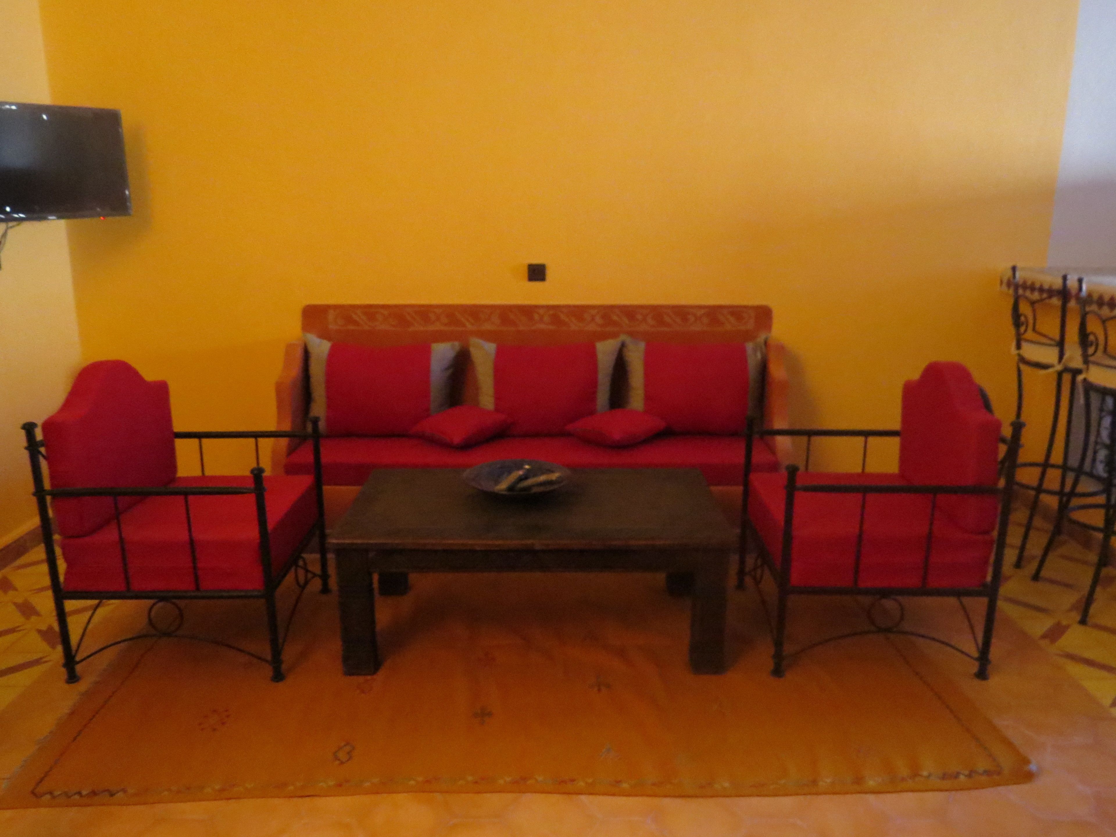 A living room with a sofa set, a coffee table, and a TV mounted on the wall.
