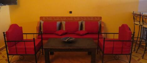 A living room with a sofa set, a coffee table, and a TV mounted on the wall.
